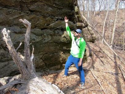 Image of man gesturing towards a rock face.