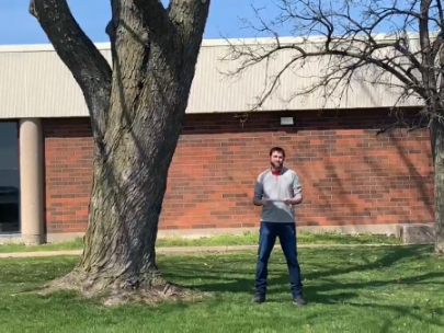 Image of man standing next to a large tree.