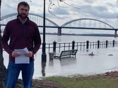 Image of man standing next to flooded Mississippi River.