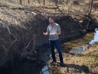 Image of man standing next to a stream bank.