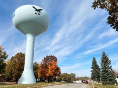 A water tower in a town on a fall day.