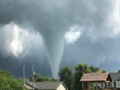 A tornado funnel behind a few houses.