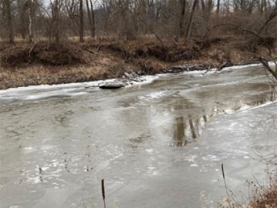 A partially frozen river. There is a little bit of snow along the far bank. 