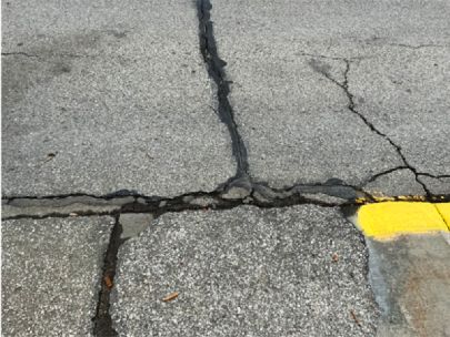 Cracks in a road or parking lot that have been filled with tar and opened more.