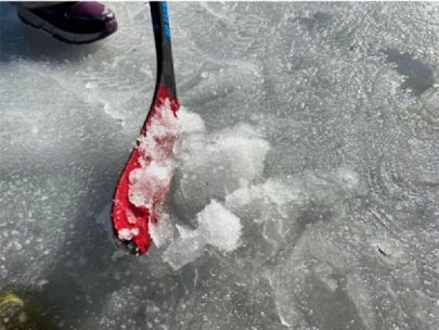 Slushy ice on a pond, piled together with the blade of a hockey stick