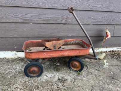 A red, rusty, child's wagon with a rusty toy grain bin inside.
